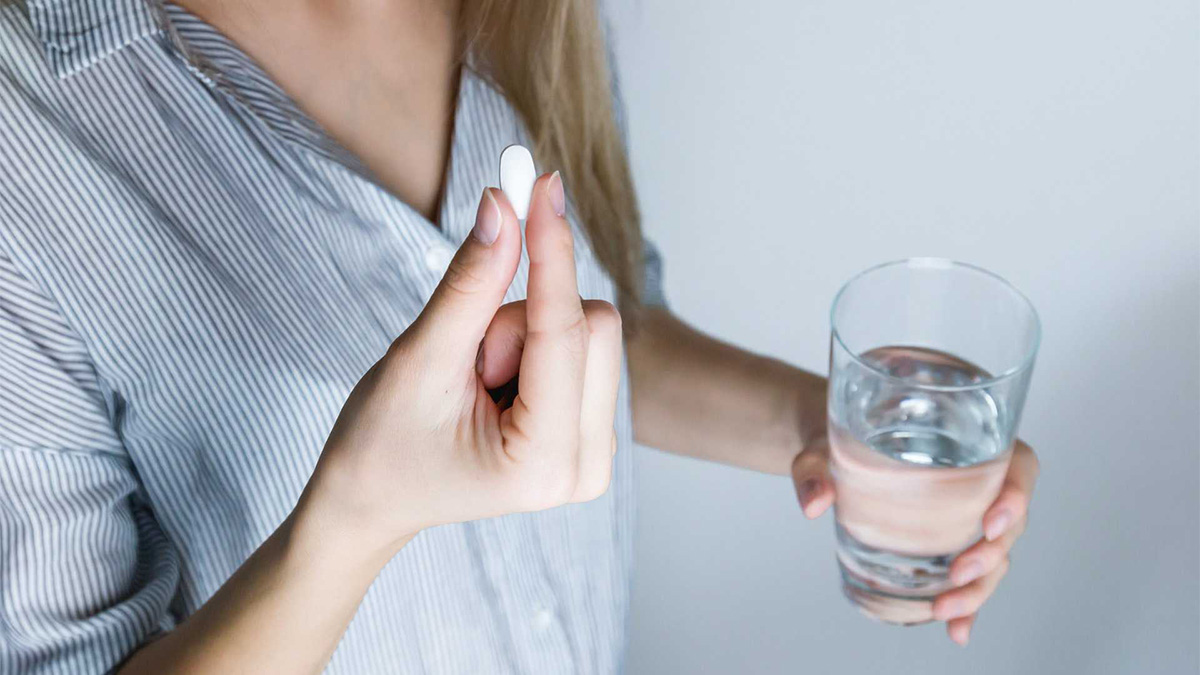 Image of a Woman holding water and medication