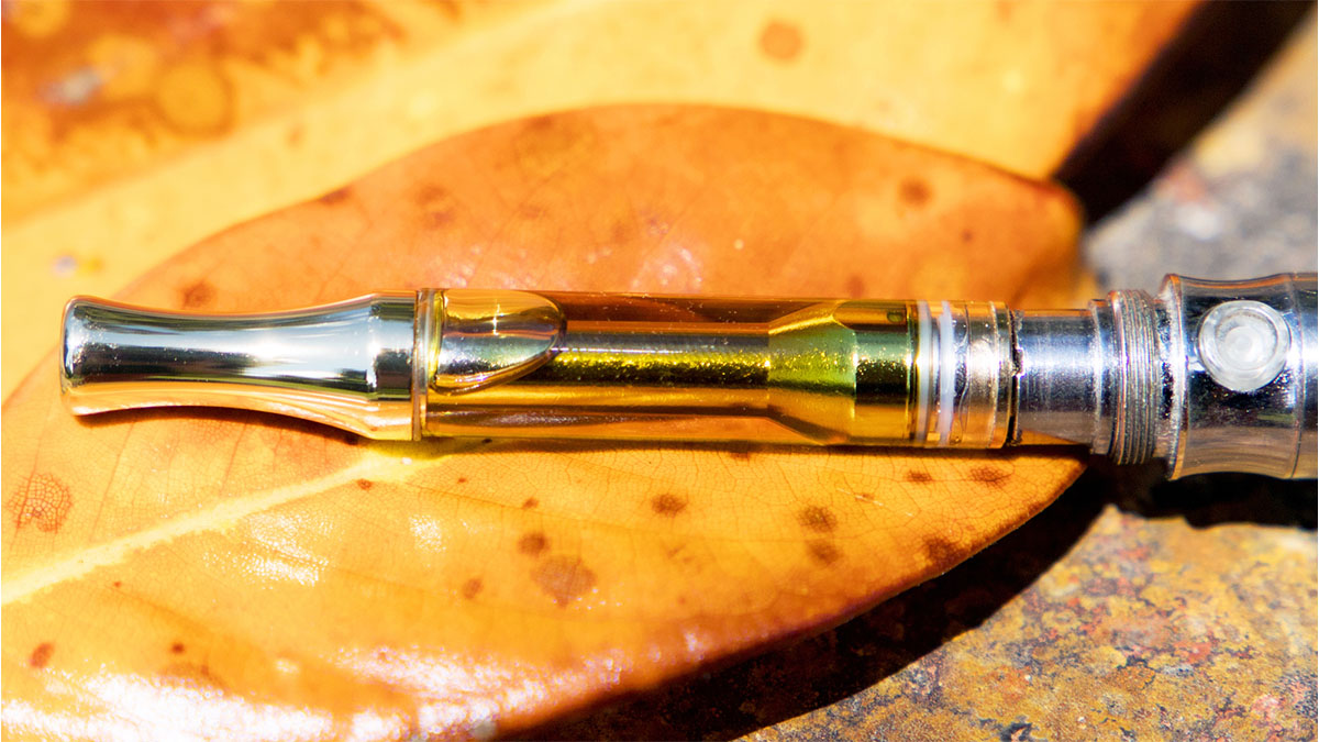 Heavy hitters vape cart on top of a yellowish brown leaf