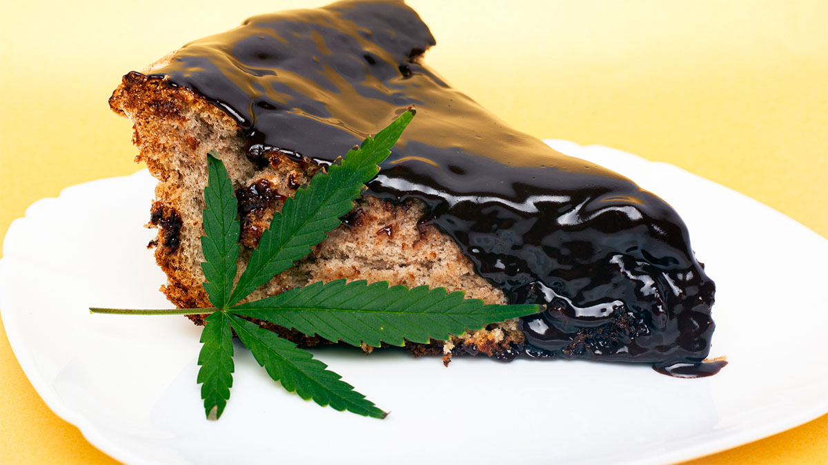 A slice of space cake with a cannabis leaf on a white plate