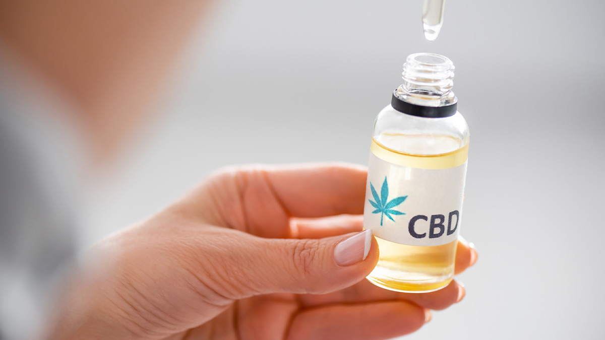 Selective focus of a woman holding a bottle of cbd oil with a dropper