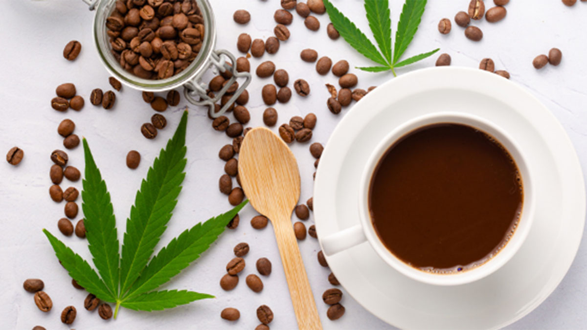 A cup of coffee with beans scattered on the table and marijuana leaves.