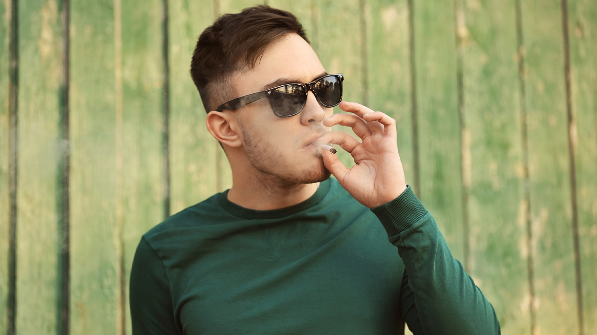 A man wearing glasses and smoking weed