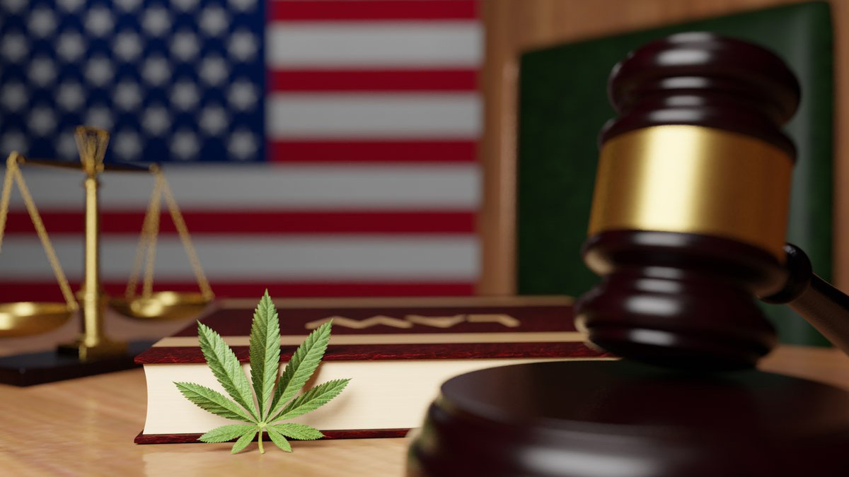 Gavel with marijuana leaf, a balance and US flag on the background.