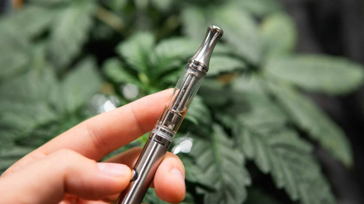 Close up of THC vape pen with with marijuana background.