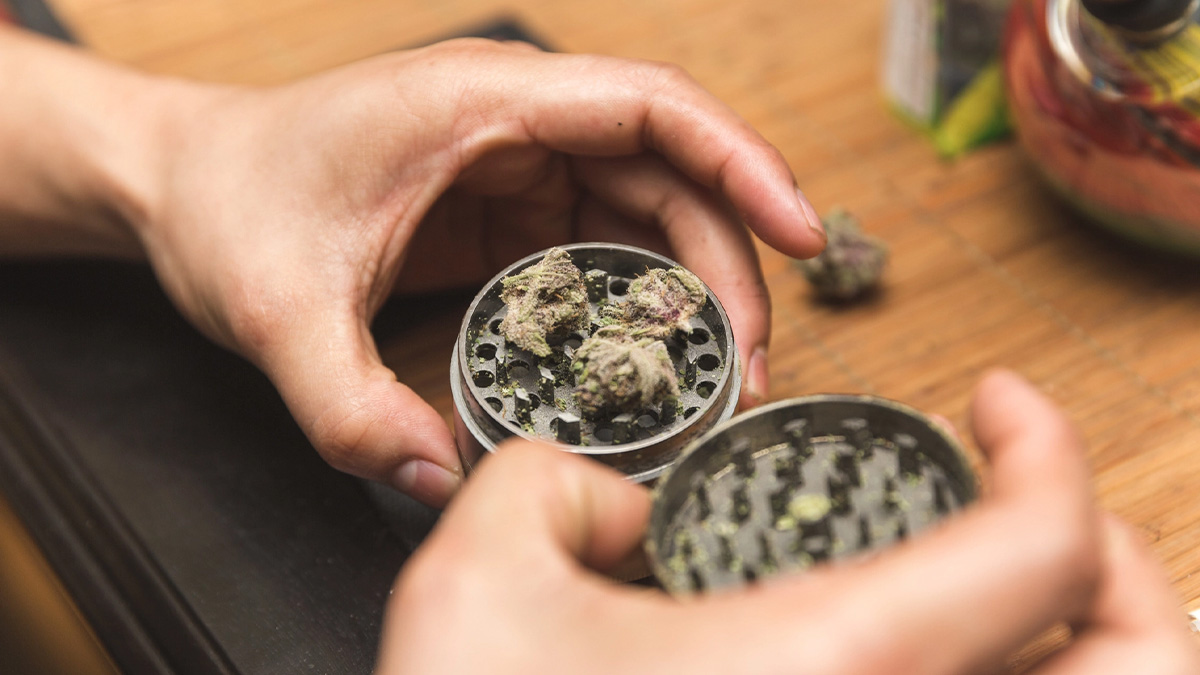 Close of a man holding a weed grinder.